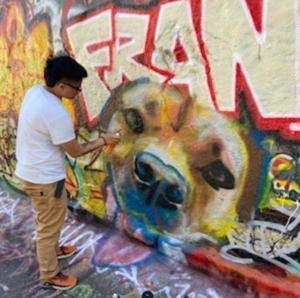 An image of artist Nofo Porter creating a mural