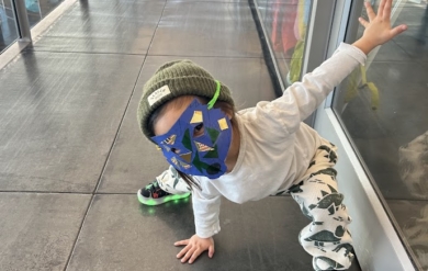 A child in a handcrafted mask in a Spiderman pose